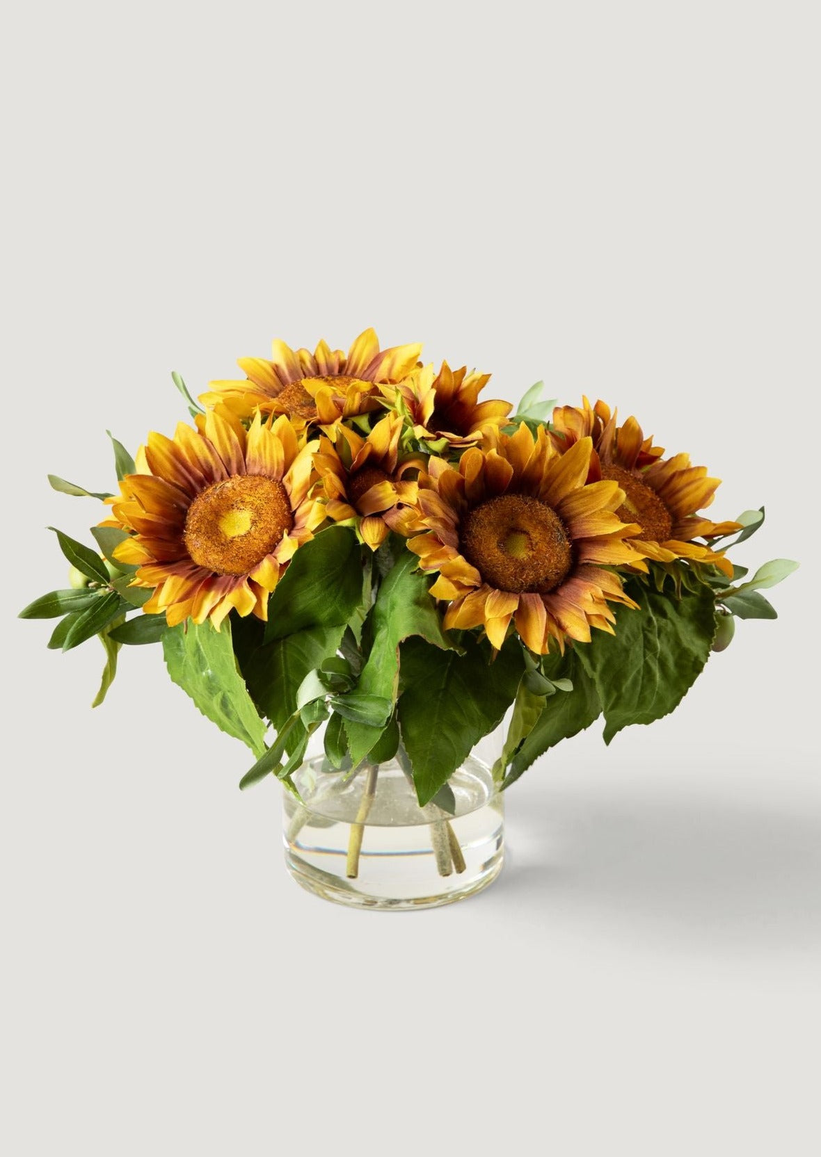 Arrangement of newest 7 artificial sunflowers in water in transparent glass vase