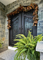 front door decorated with artificial magnolia leaf garland